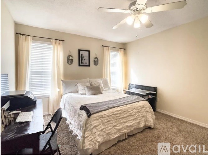 A bedroom with a bed, chair, and a ceiling fan.