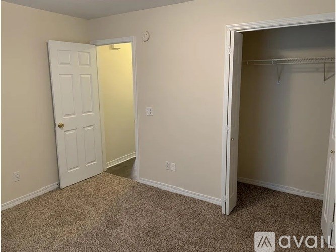 A room with a white door and a white closet with a hanger.