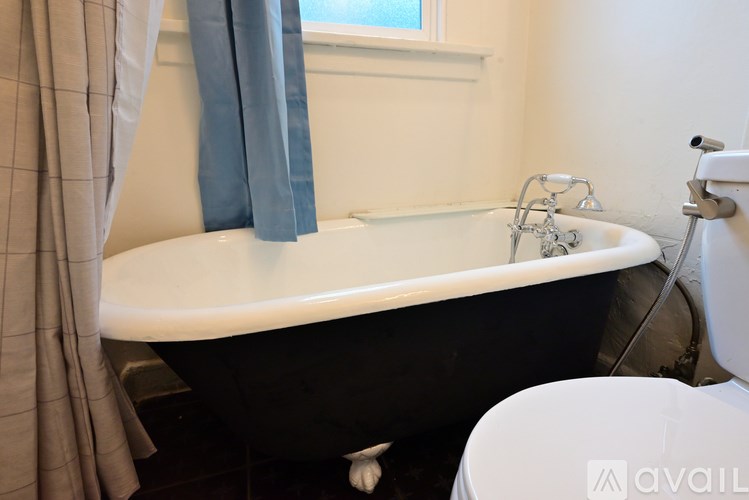 A black bathtub with a shower head and a towel hanging on the side.
