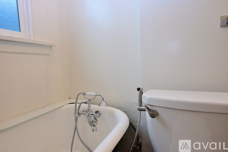 A white bathtub with a shower head and a window above it.