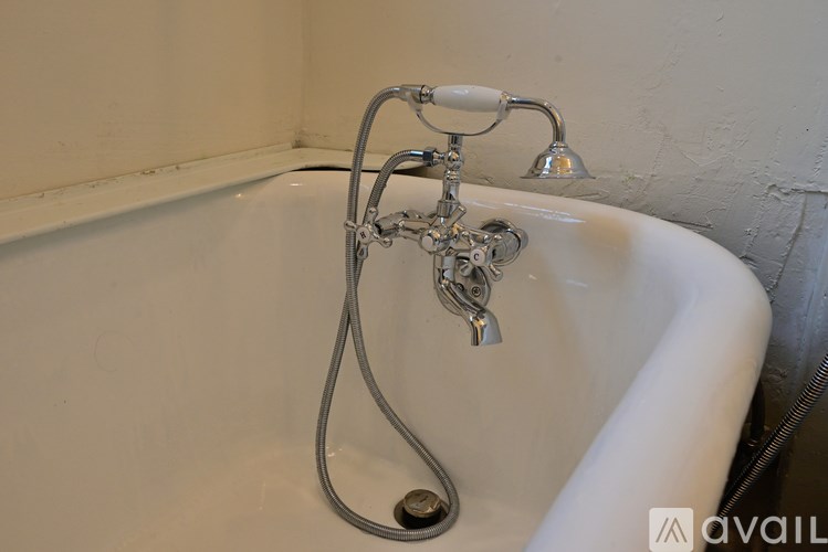 A white bathtub with a shower head and hand shower.