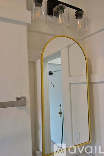 A mirror with a yellow frame is hanging on a wall above a white door.
