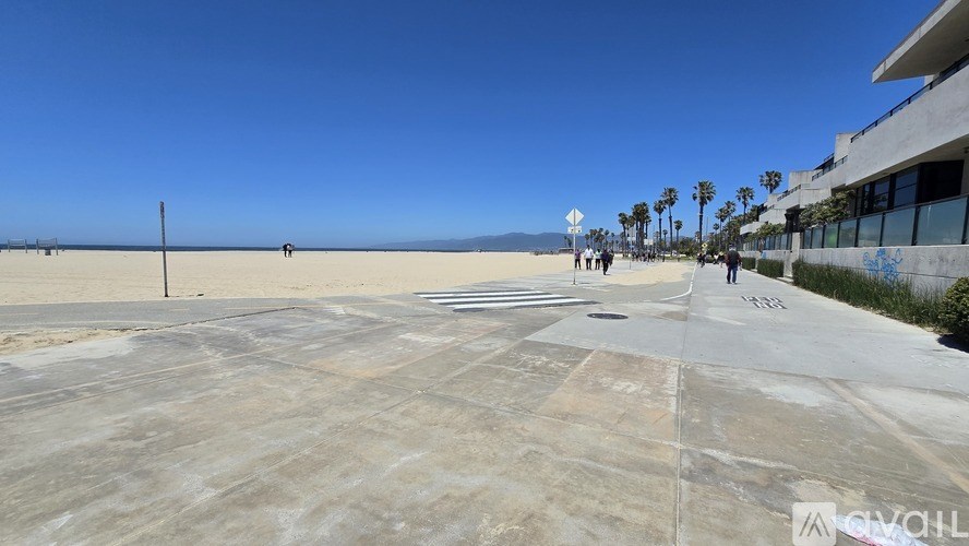 A concrete area with people walking around and a building on the right side.