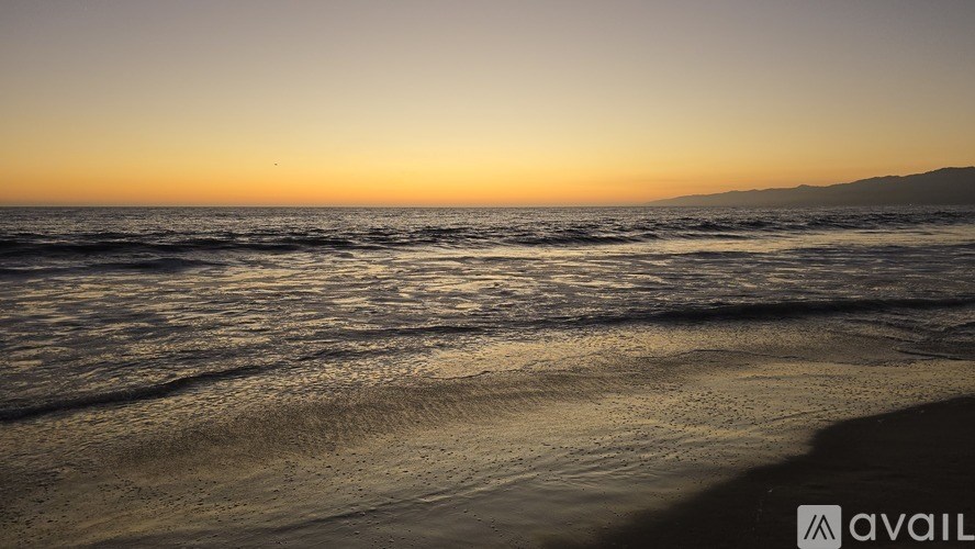A beach at sunset with waves gently rolling in.