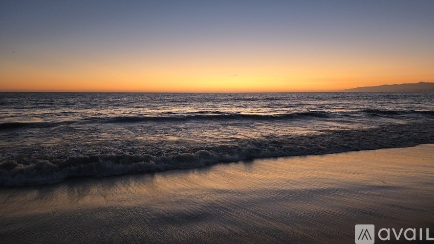 A beach at sunset with waves gently coming onto the shore.