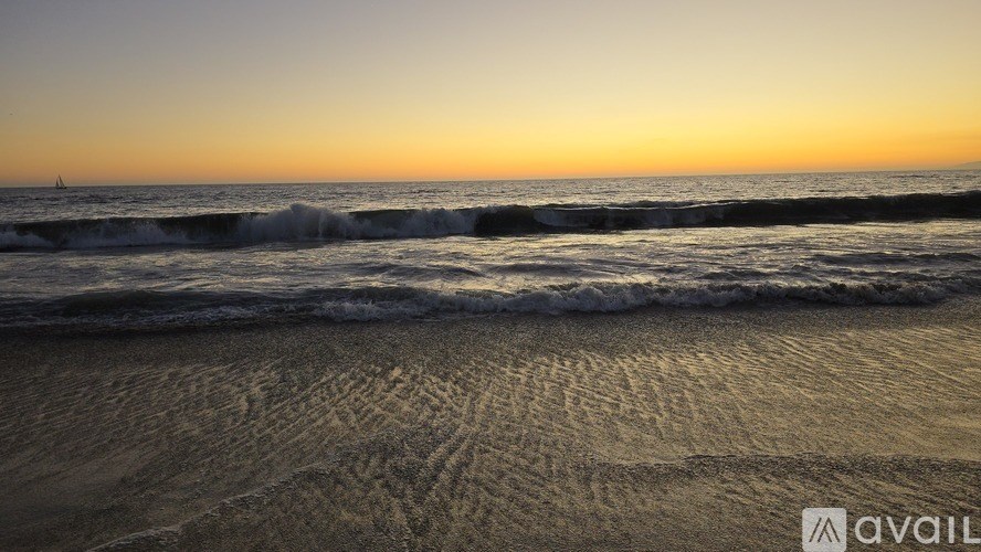 A beach at sunset with waves coming in.