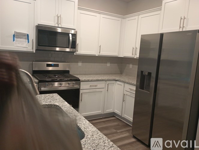 A kitchen with white cabinets and a stainless steel refrigerator.