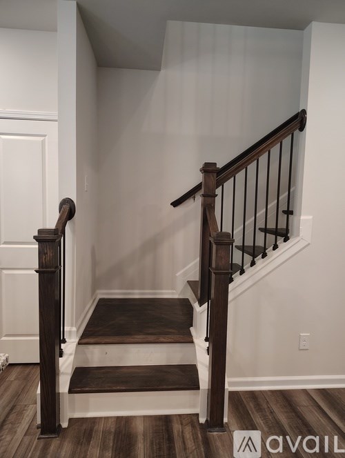 A wooden staircase with a black railing and a white door.