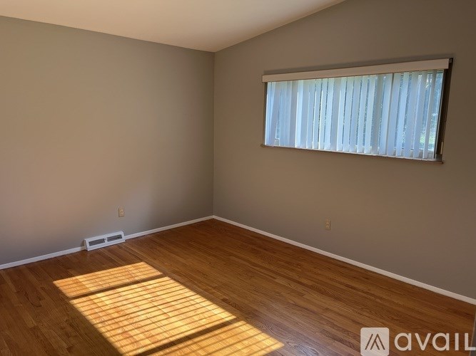 A room with wooden flooring and a window with blinds.