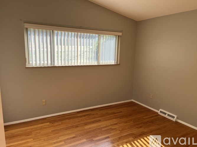 A room with wooden flooring and a window with blinds.
