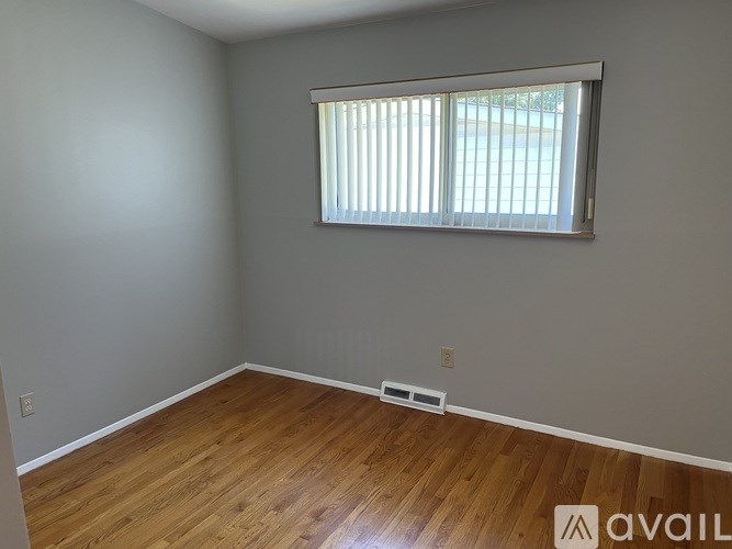 A room with wooden flooring and a window with blinds.
