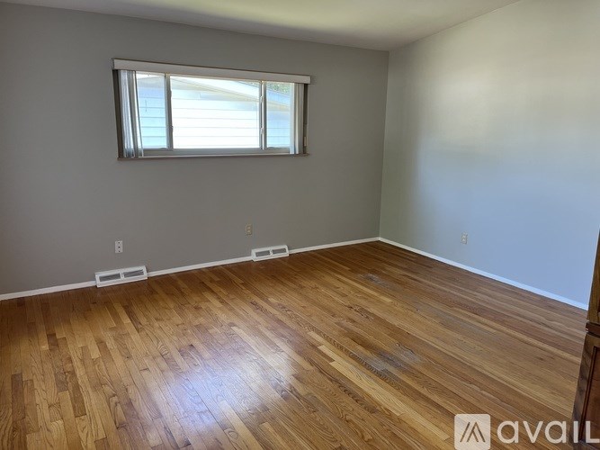 A room with wooden flooring and a window with blinds.