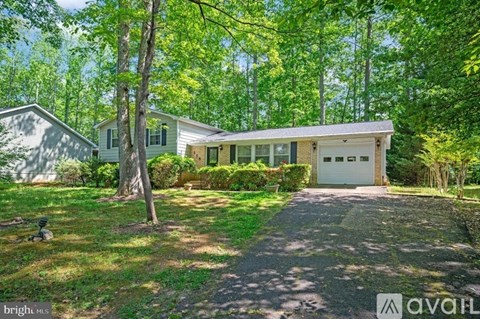 A house with a driveway and a tree in front of it.