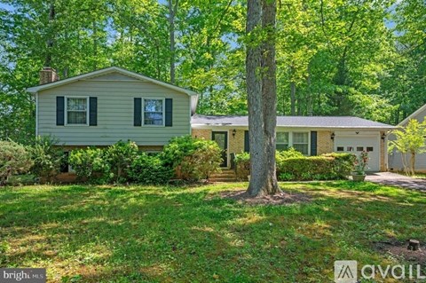 A house with a green lawn and trees in the background.