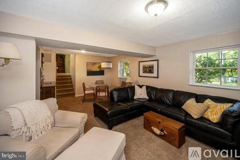 A living room with a black couch and a white chair.
