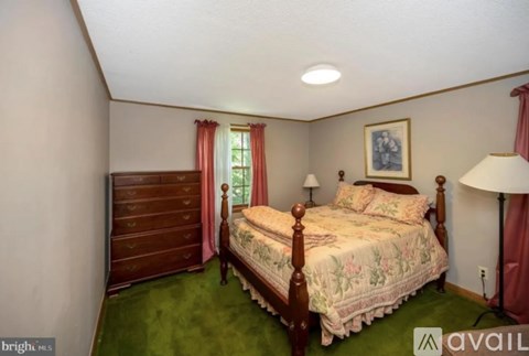 A bedroom with a bed, dresser, and window.