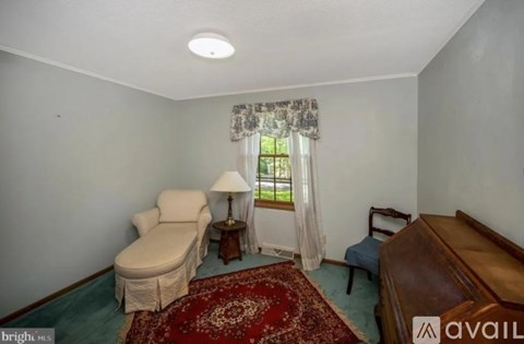 A living room with a sofa, chair, and a table with a lamp on it.