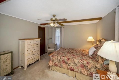 A bedroom with a floral bedspread and a ceiling fan.