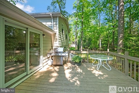 A house with a deck and a glass table surrounded by trees.