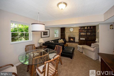 A living room with a glass table and chairs, a couch, a fireplace, and a bookshelf.