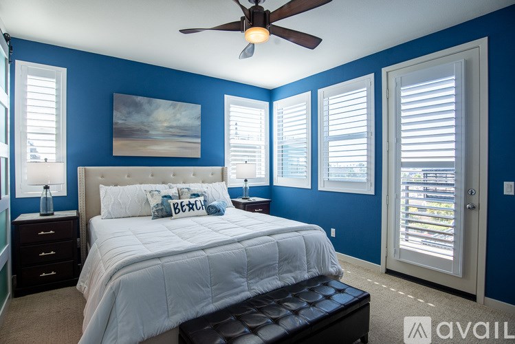 A bedroom with a large bed, a ceiling fan, and a painting on the wall.
