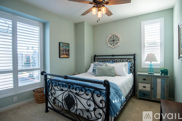 A bedroom with a bed, nightstand, and window with blinds.
