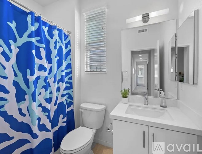 A bathroom with a blue shower curtain and a white toilet.