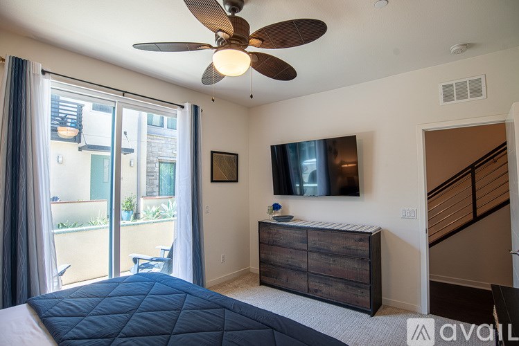 A bedroom with a bed, a ceiling fan, and a television.