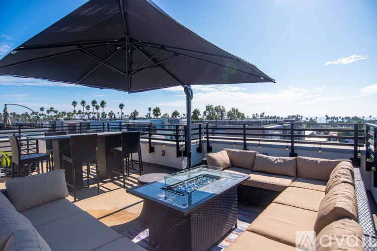 A large umbrella shades a table and chairs on a patio.