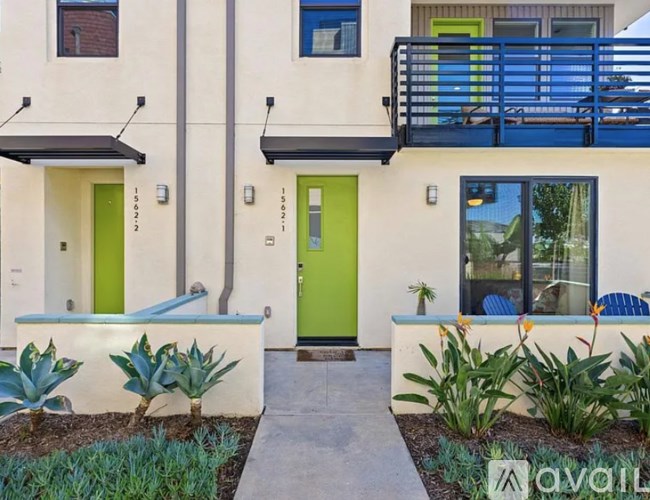 A modern house with a green door and plants in front.