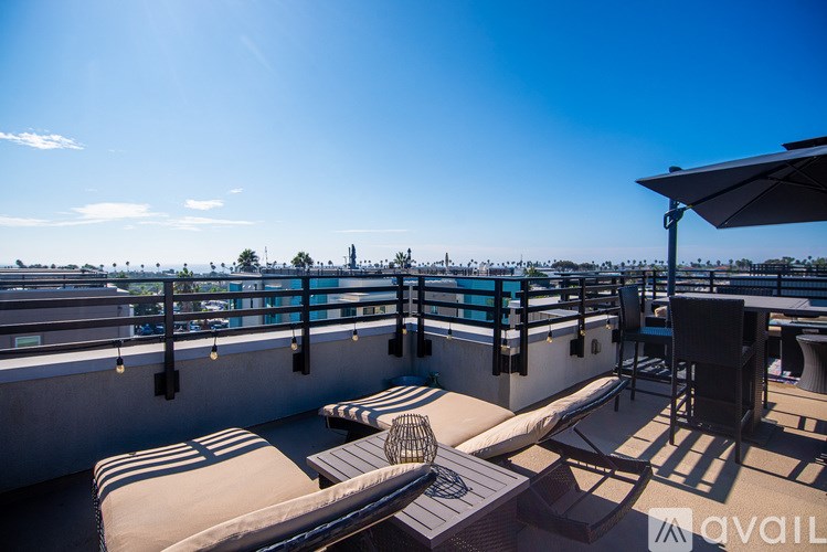A sunny day at the rooftop pool with chairs and a table.