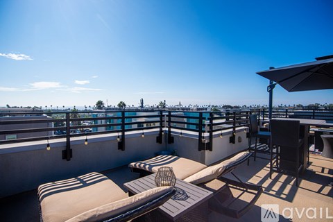 A sunny day at the rooftop pool with chairs and a table.