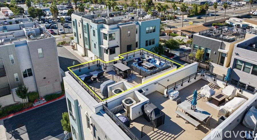 A rooftop patio with a table and chairs is surrounded by buildings.