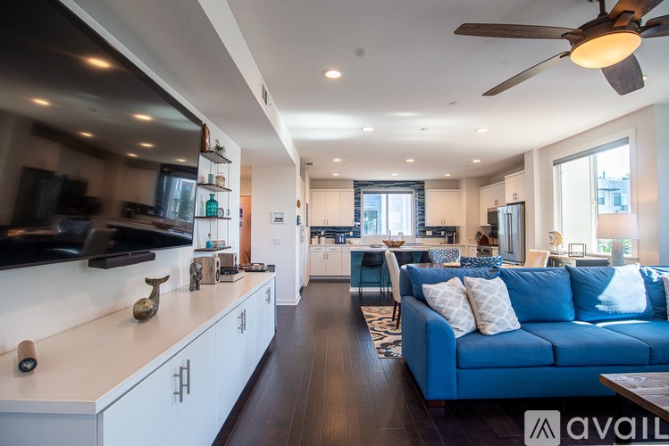 A modern kitchen with a blue couch and a ceiling fan.