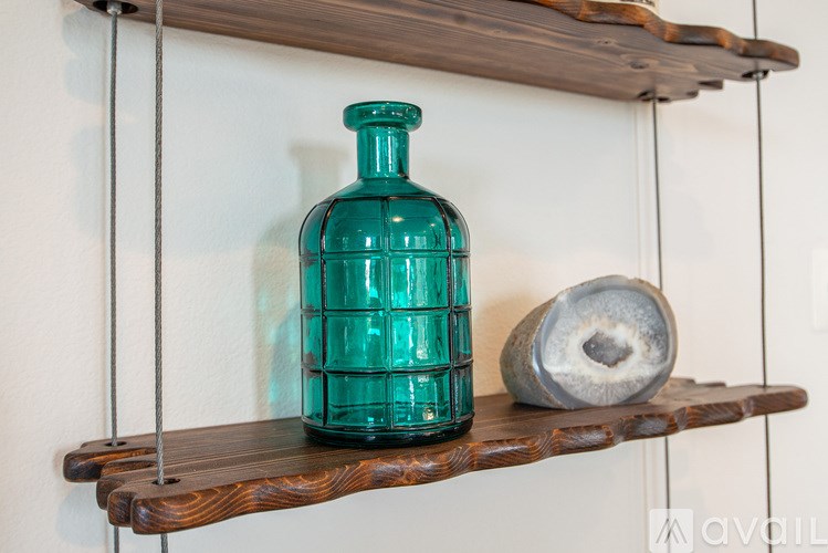 A green bottle is on a shelf next to a grey object.
