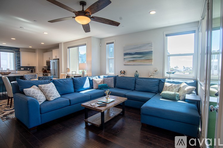 A living room with a blue couch and a ceiling fan.