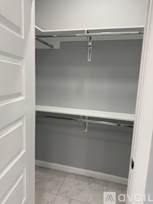 A white closet with a grey shelf and a white door.