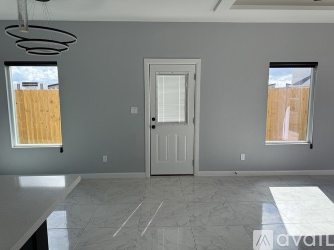 A room with a white door, two windows with wooden blinds, and a marble floor.