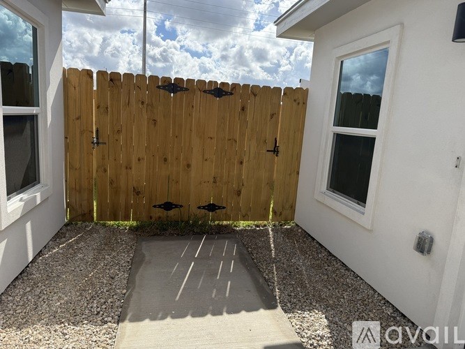 A wooden fence with a gate and a small garden area.