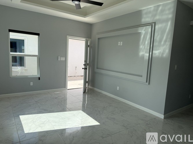 A spacious room with a marble floor and a ceiling fan.