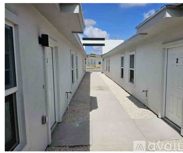 A long white building with a gravel path down the middle.