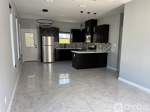 A kitchen with a marble floor and a refrigerator in the middle.