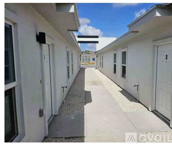 A row of white houses with a gravel path between them.
