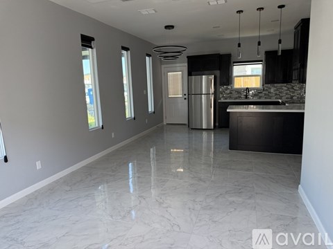 A kitchen with a marble floor and a refrigerator in the middle.