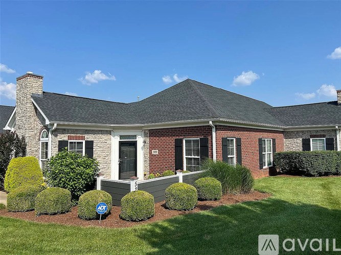 A house with a brick facade and a green lawn in front.