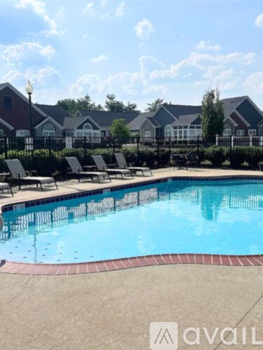A pool surrounded by lounge chairs and a building in the background.