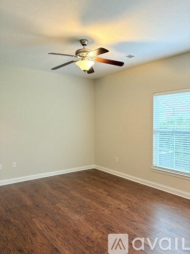 A room with white walls and wood flooring with two white shelves.