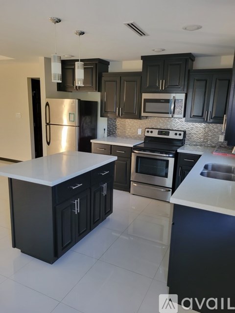 A kitchen with black cabinets and a white countertop.