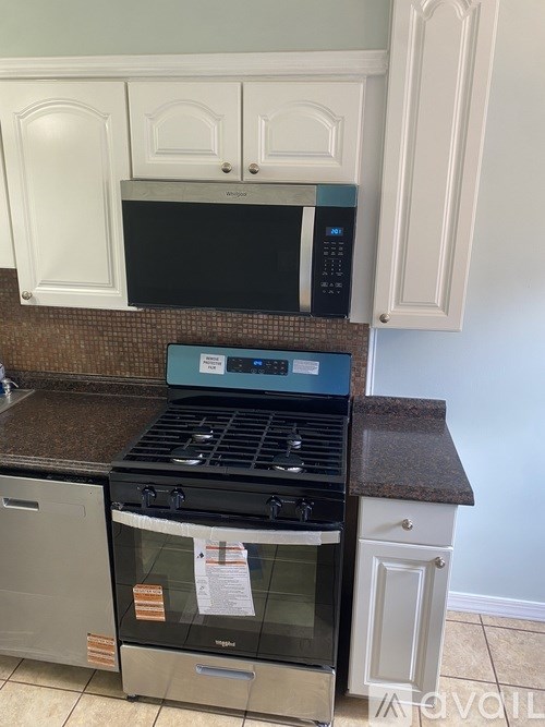 A kitchen with a black stove top oven and a black microwave above it.