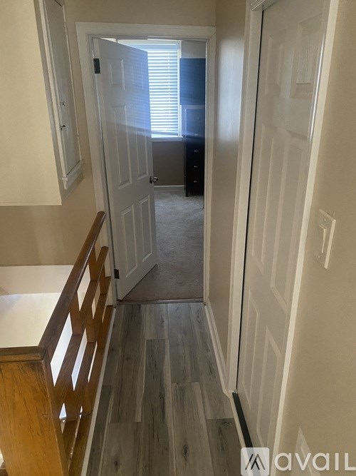 A hallway with a wooden staircase and white walls.